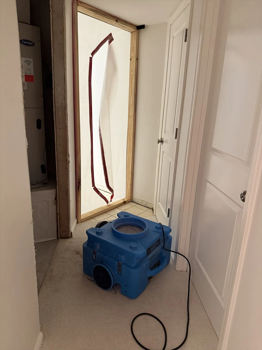 HEPA air scrubber in a closet with a plastic containment door