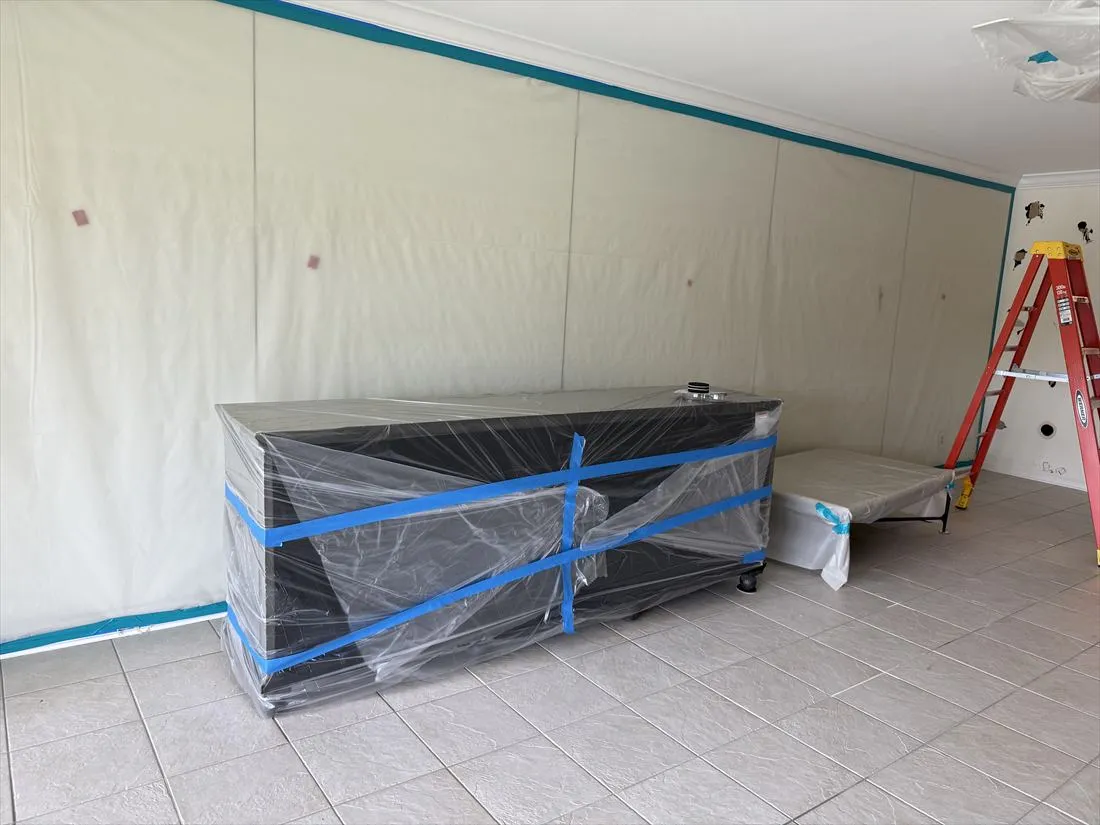 Room sealed in plastic with teal tape, furniture wrapped