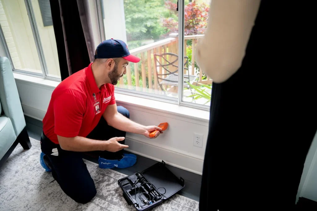 Technician inspecting window frame for moisture damage