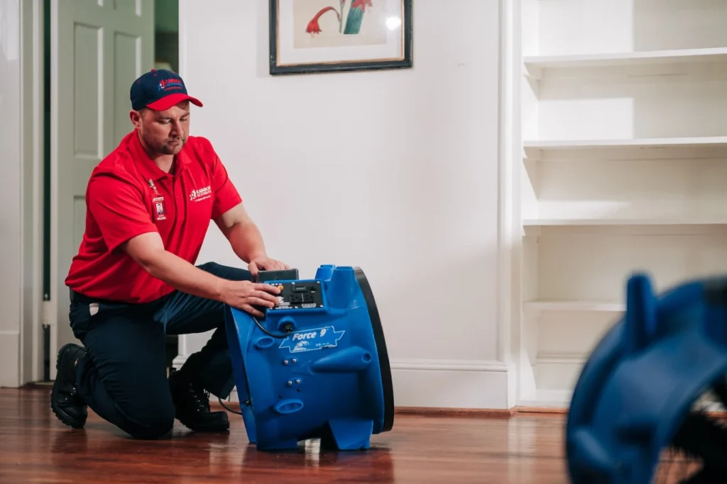 Technician setting up an air mover to dry water-damaged flooring
