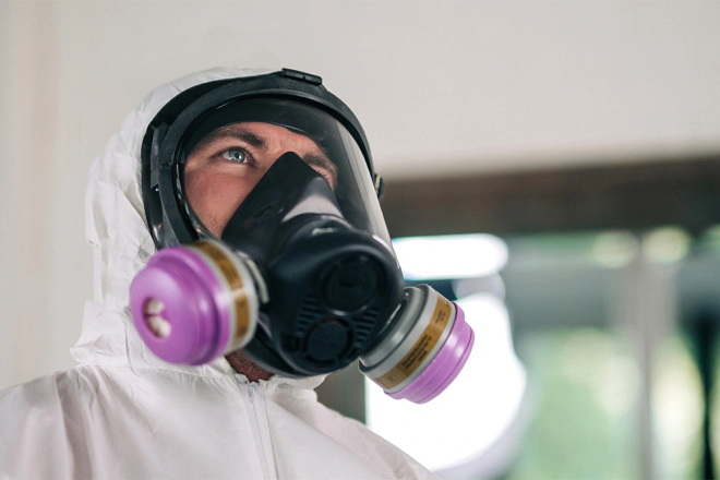 Technician in protective gear performing mold remediation